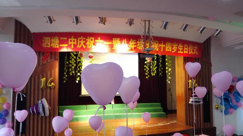 "泗塘二中庆祝六一暨八年级庆祝十四岁生日仪式"的横幅更让会场增色